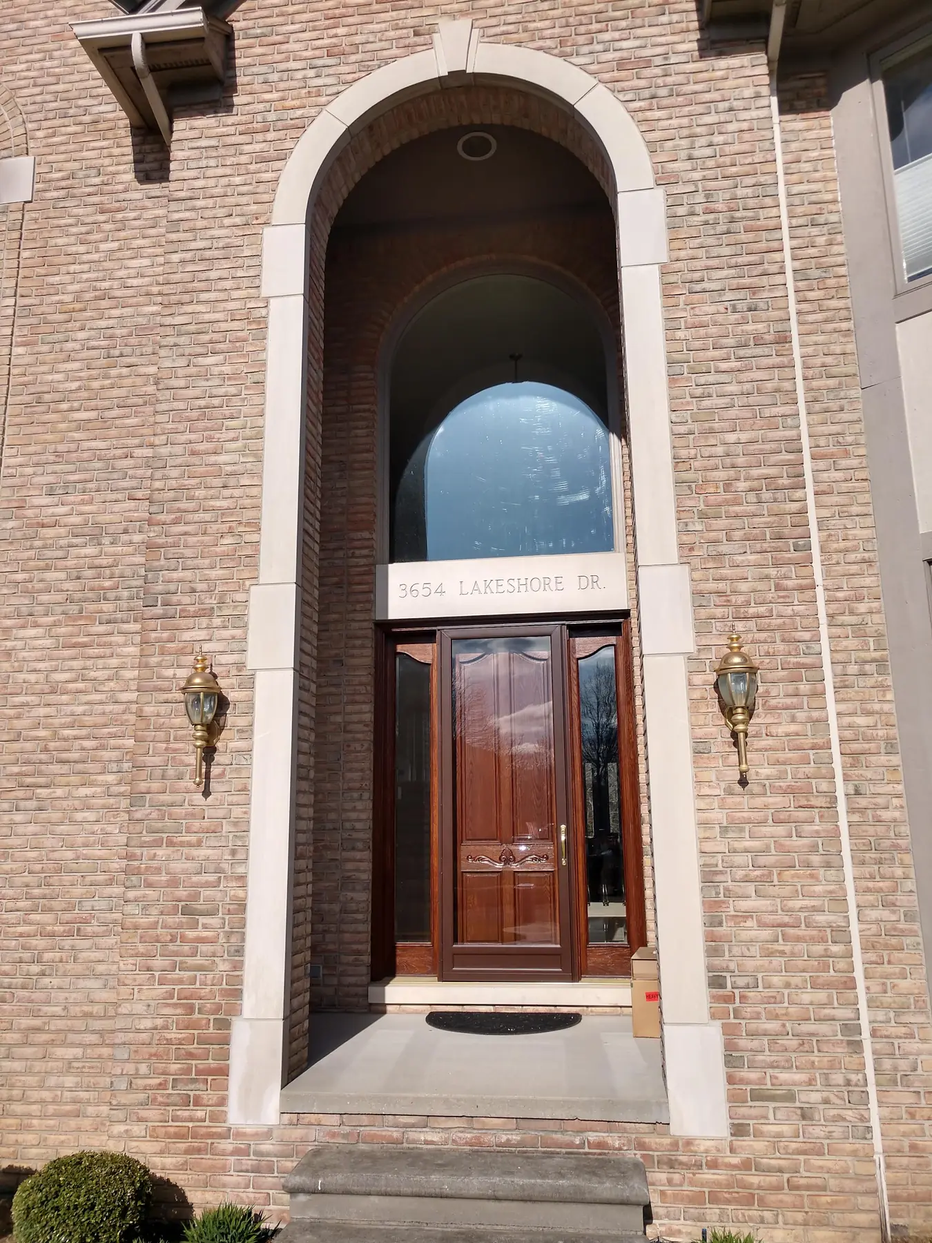 Tall arched front entry with a refinished wood door