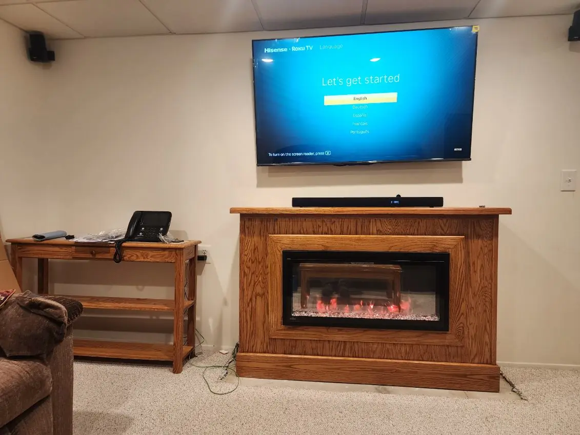 The finished surround with the electric fire lit and a TV mounted above