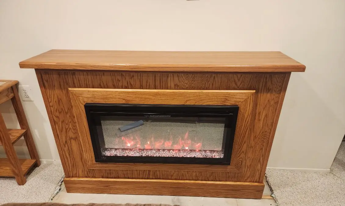 A built wood fireplace surround with an electric fire lit