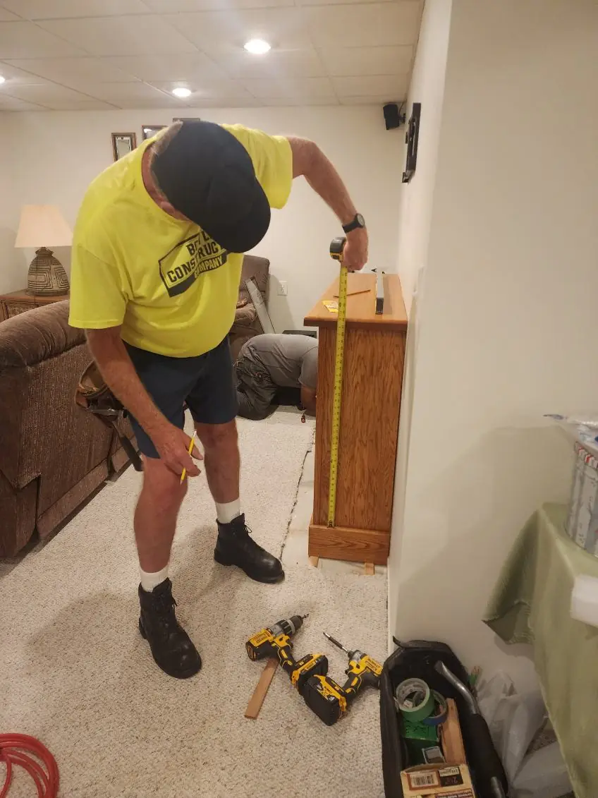 A carpenter measuring a side panel with a tape