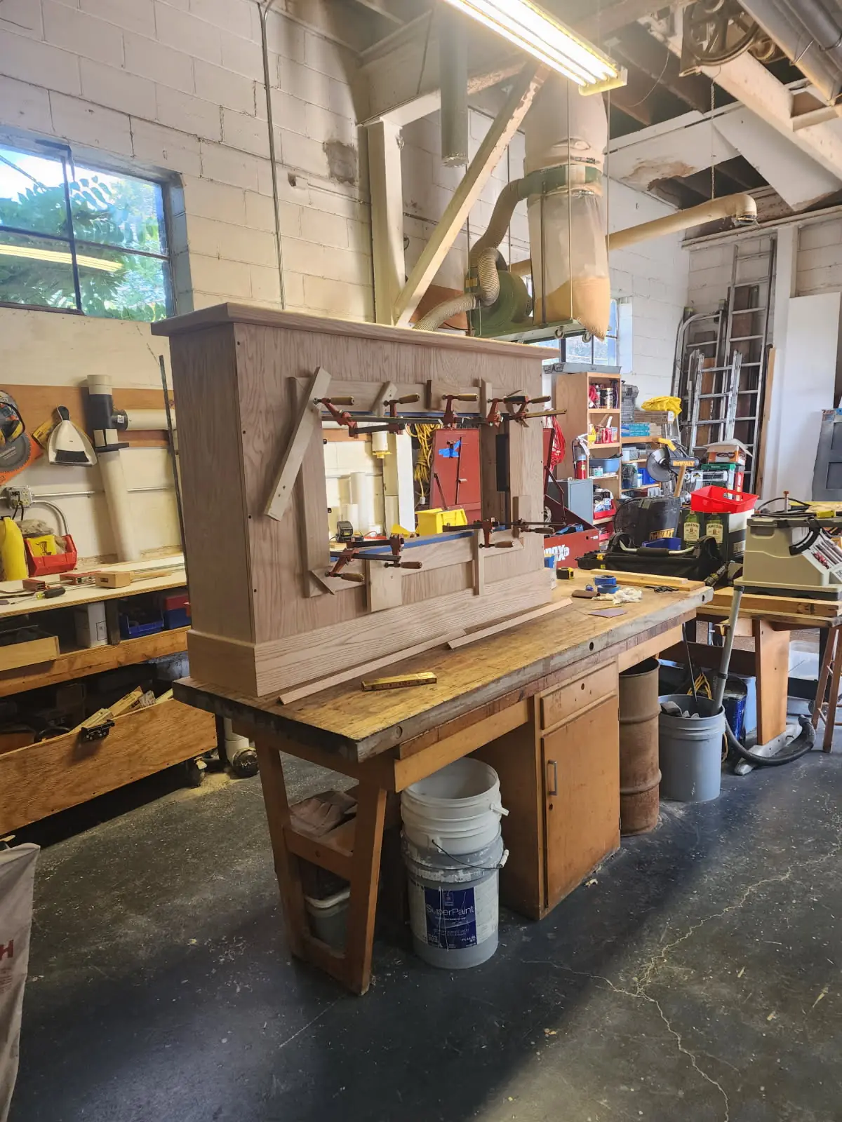 A wood fireplace surround clamped up on a workbench in the shop