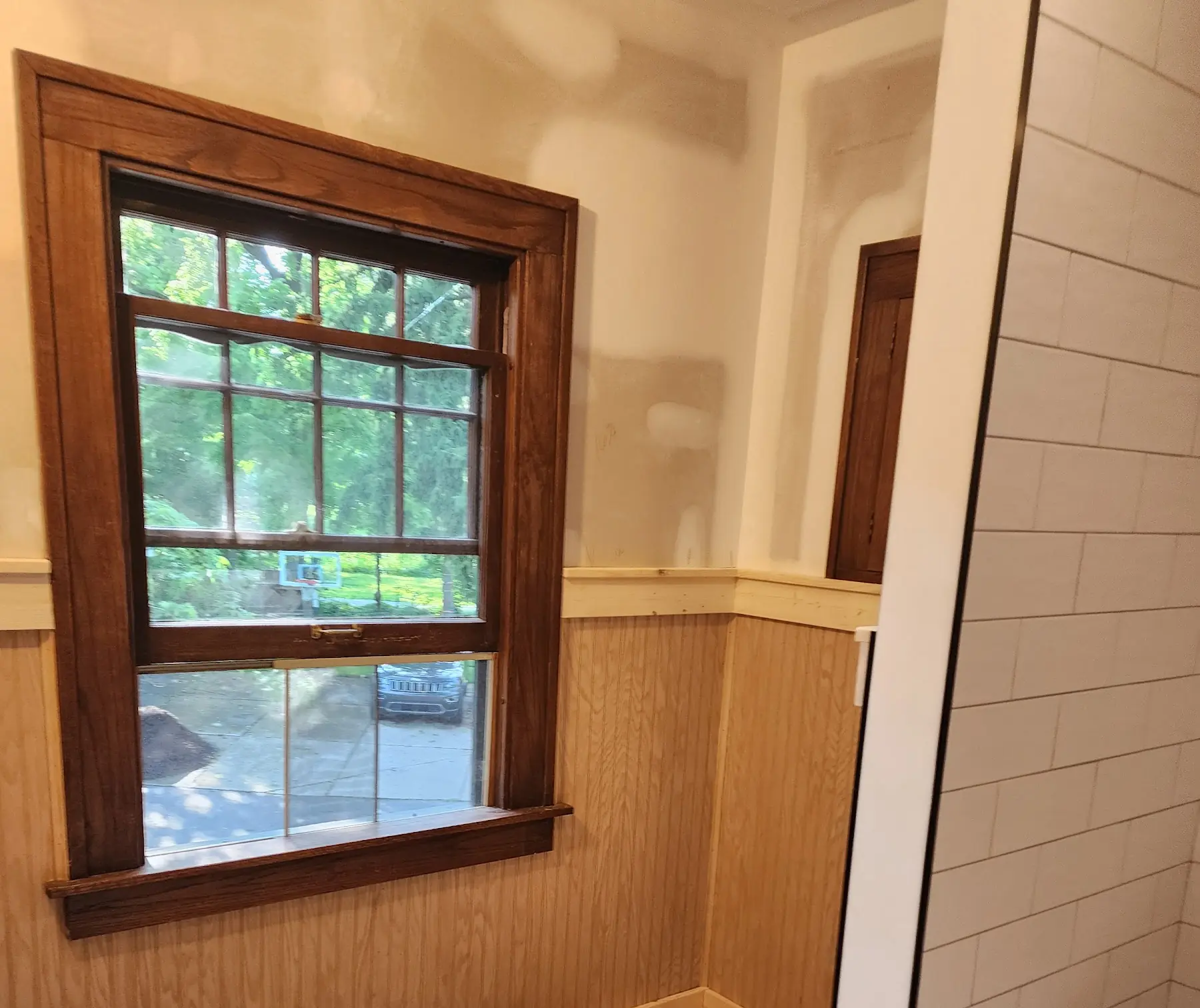 Stained window trim above unpainted beadboard, mid-renovation