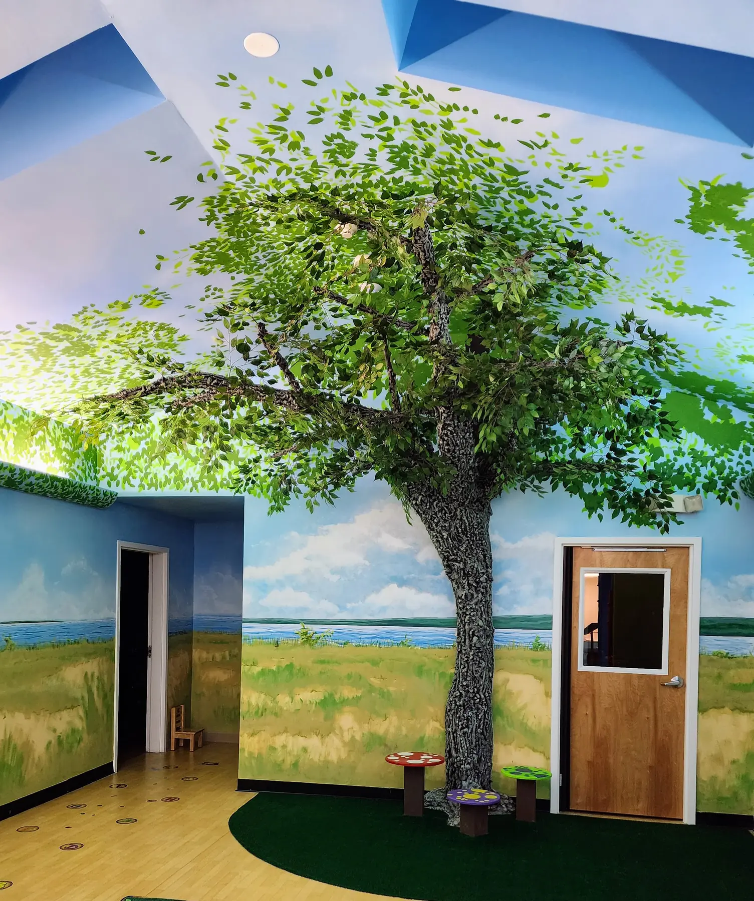 Painted tree and sky mural in a child care room