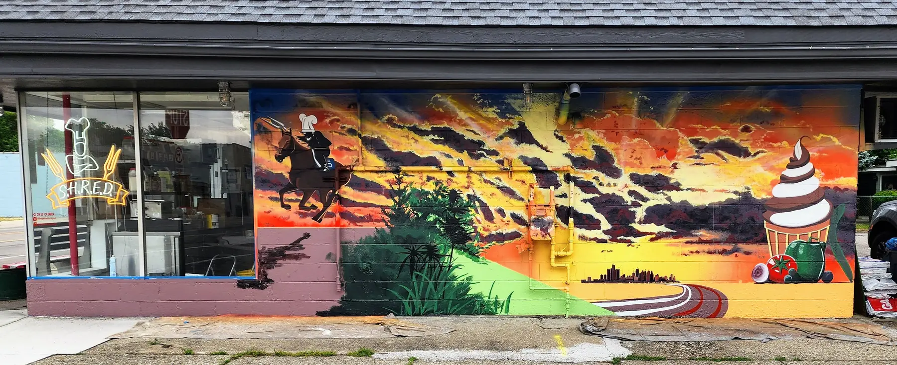 Sunset mural with a rider and an ice cream cone across a storefront